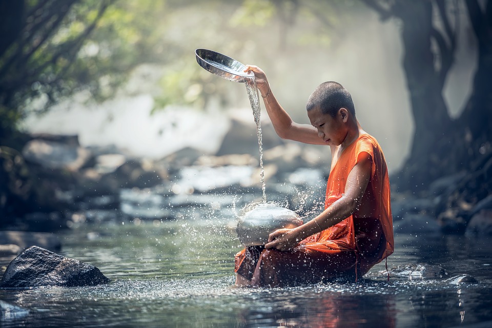 Buddhist pouring water into a stream