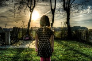 Girl stood in garden with sunlight through trees