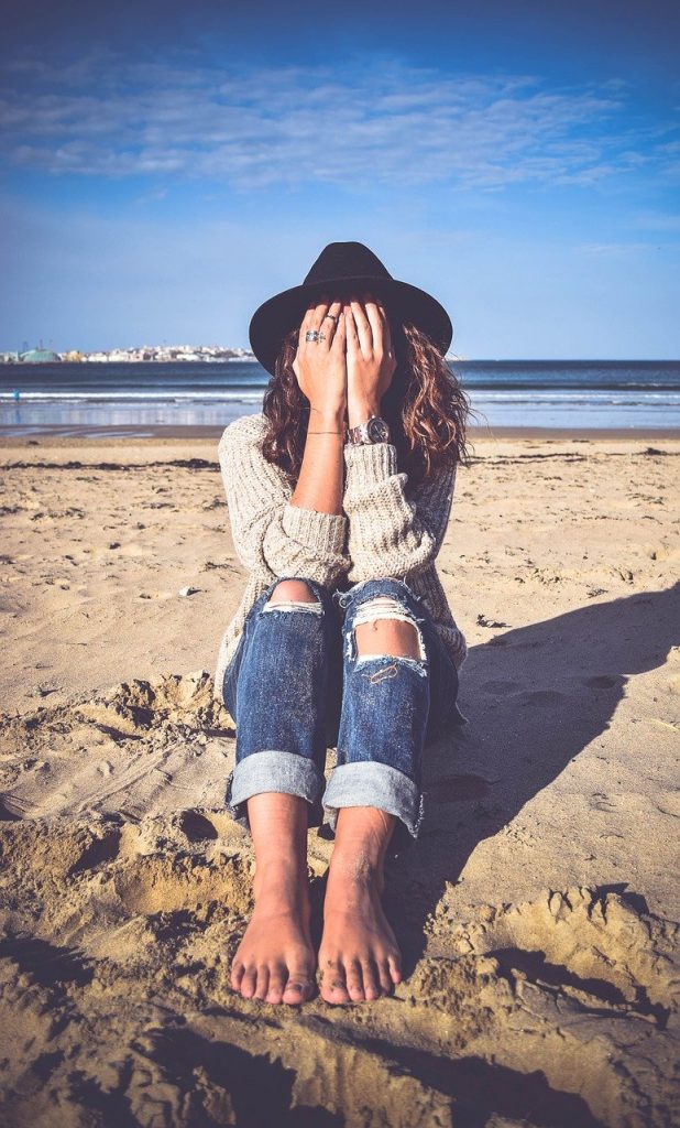 woman sat on the beach with hands over her face