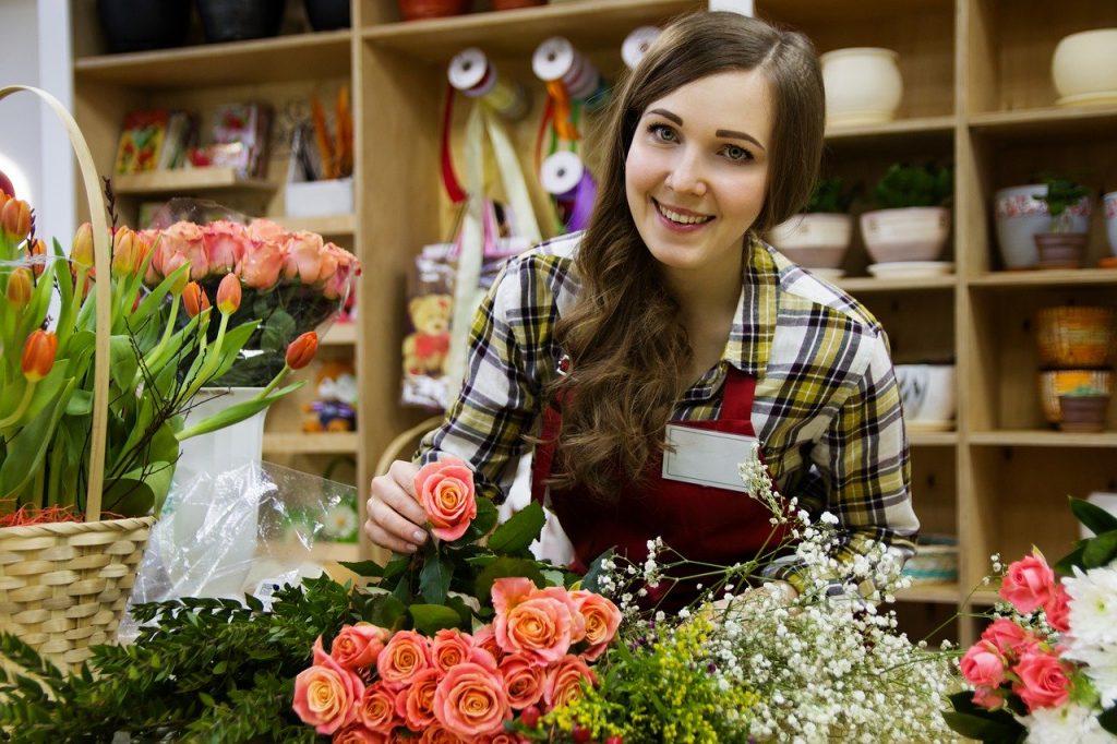 woman arranging flowers and looking happy at work due to practicing meditation and mindfulness 