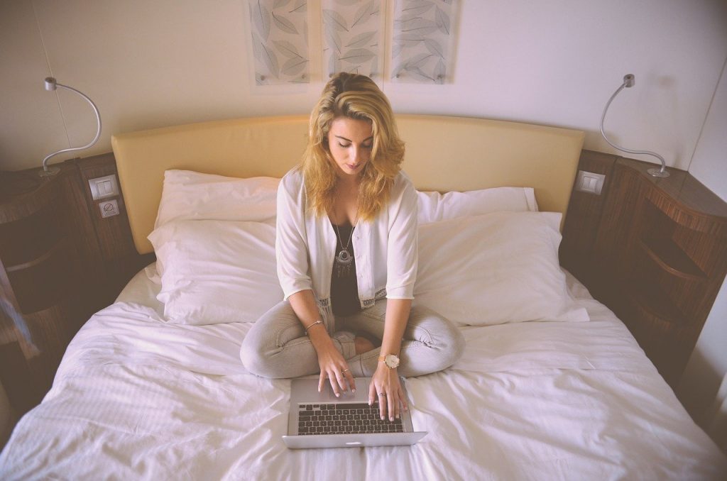 woman sat on her bed working from home