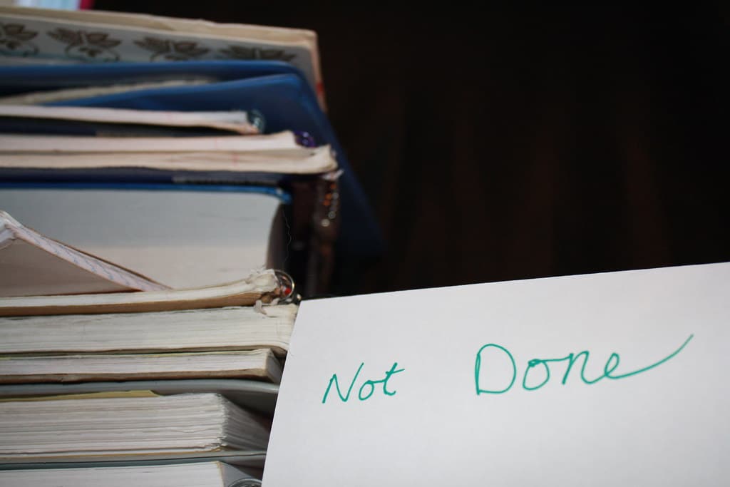 pile of books with "not done" sign next to it