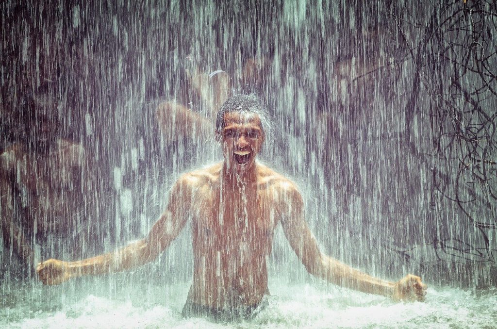 man enjoying the benefits of cold water therapy under a waterfall