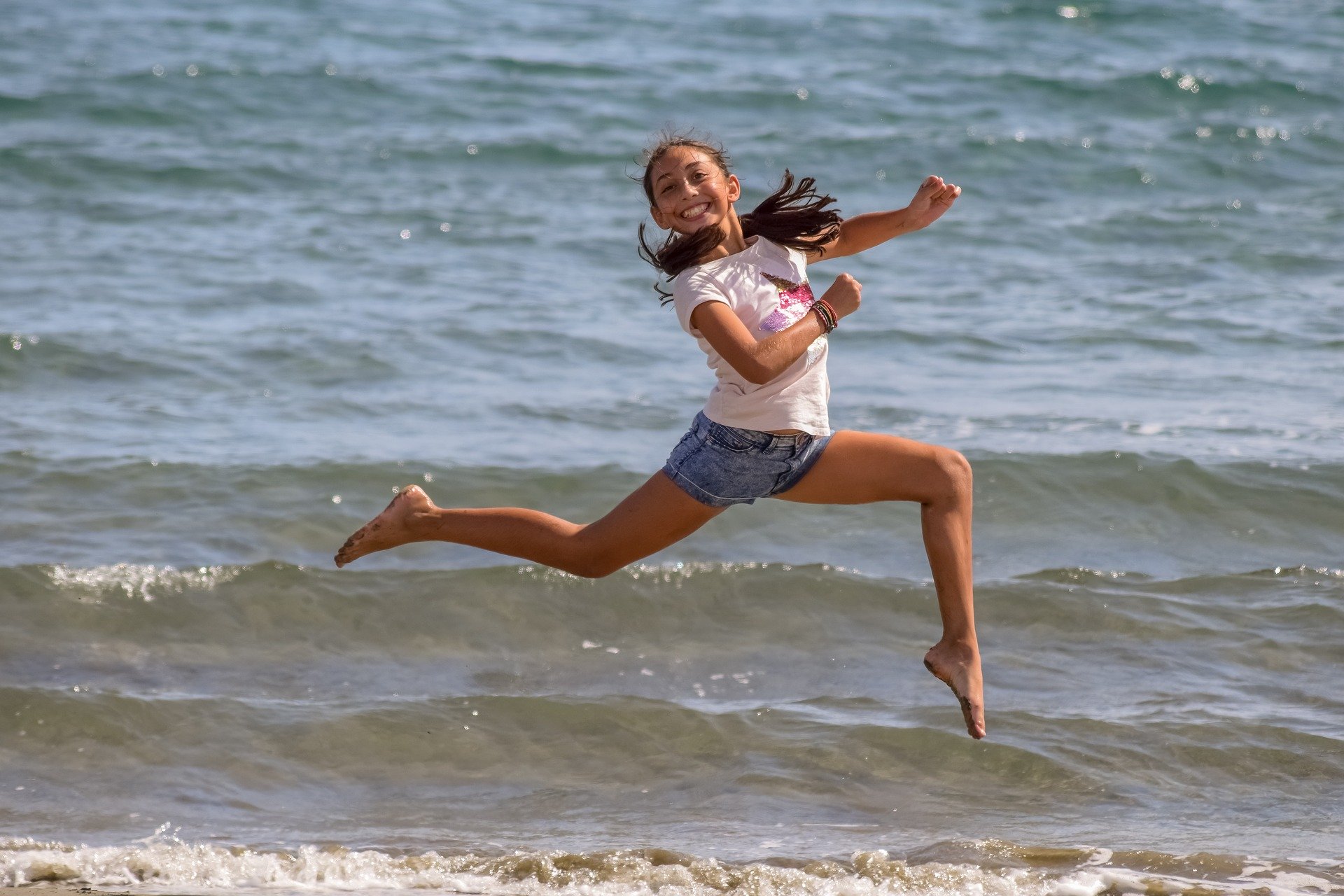 Girl jumping down the beach with more energy
