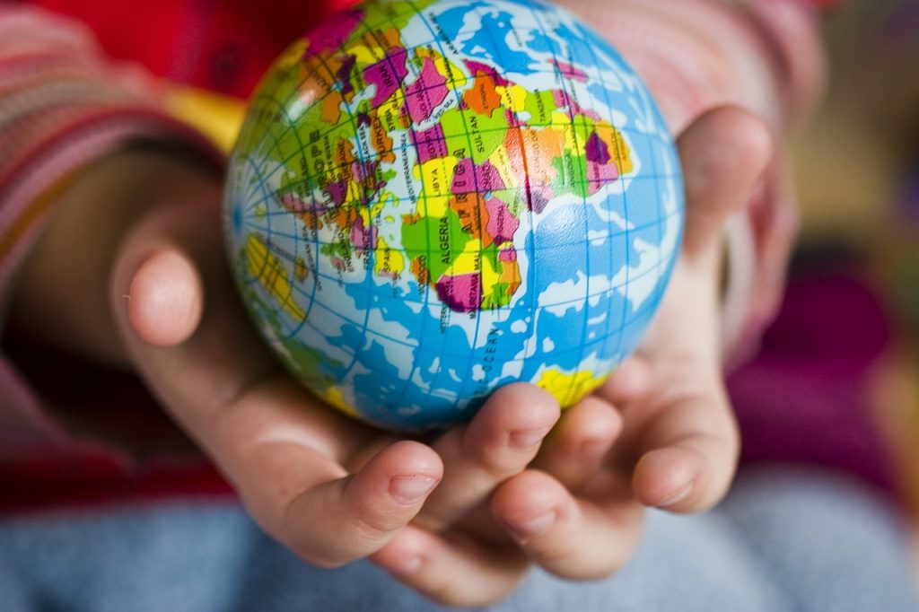 A child holding a globe - how helping others can change the world