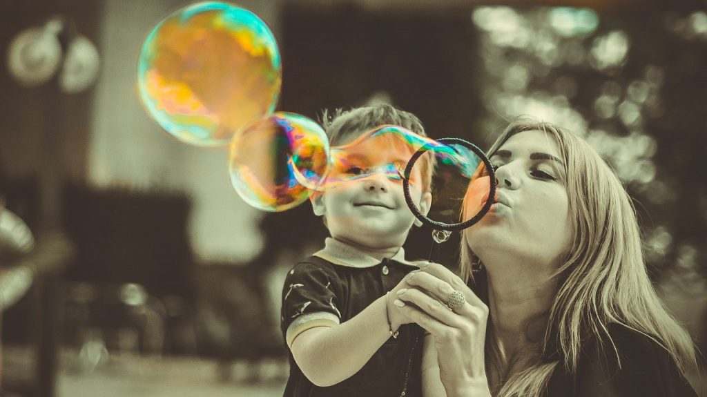 a woman blowing bubbles and spreading love with a small child