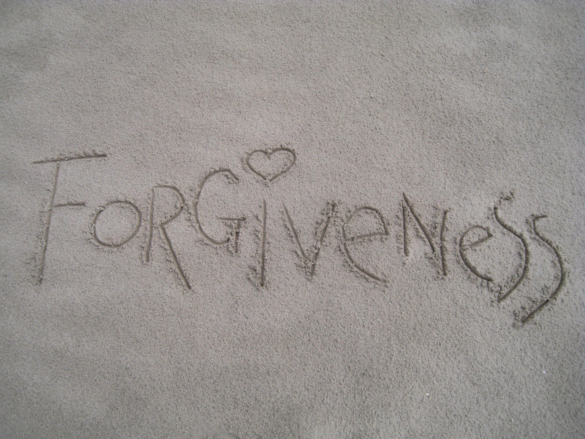 Forgiveness written in sand - title picture for article How to Practice Forgiveness