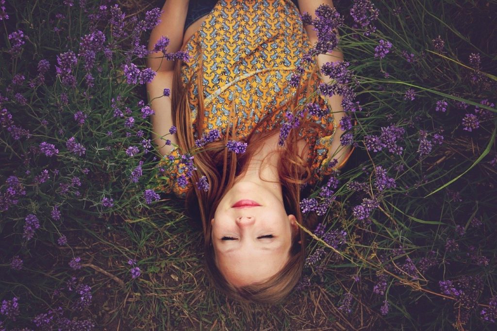 Girl lying in a field practicing positive self talk to boost her confidence