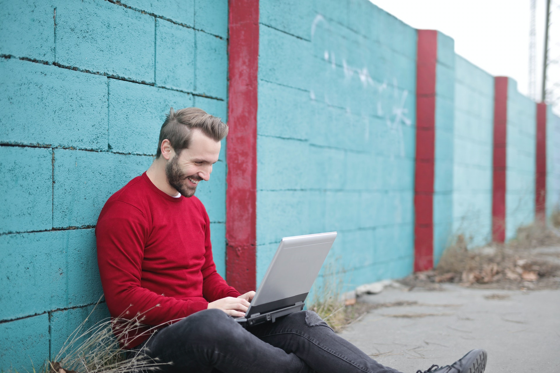 Man sitting looking at a laptop looking happy - Mental Wellbeing Websites