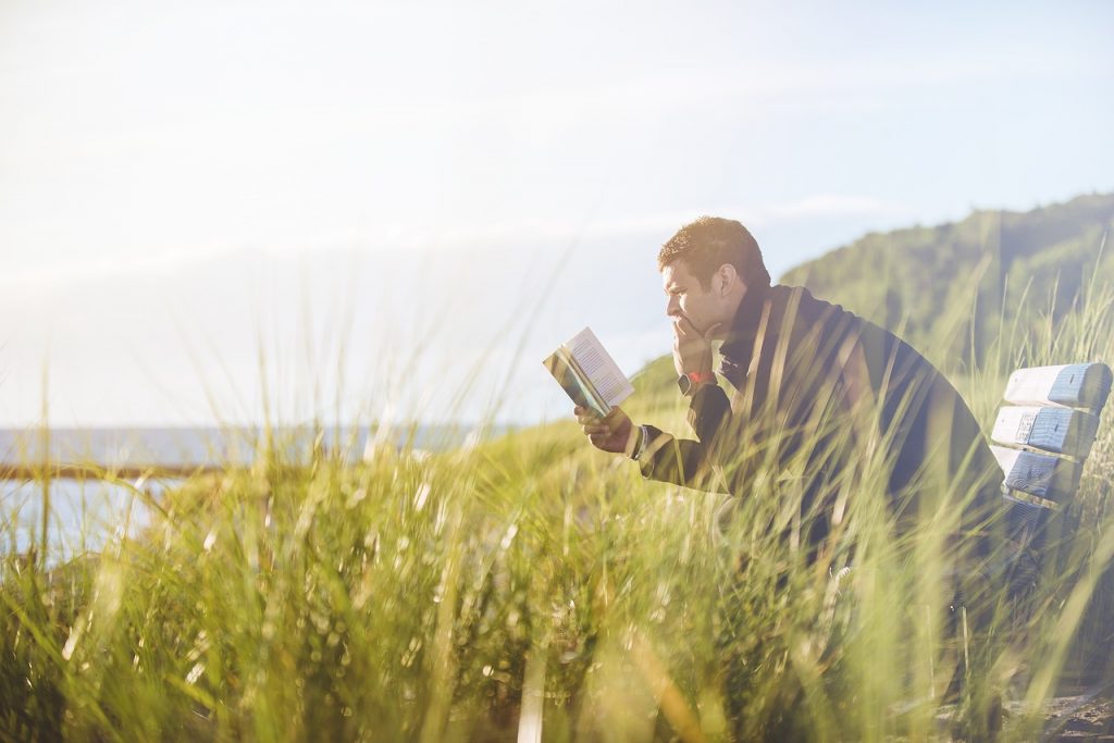 man reading book looking happy - ways to be happy alone