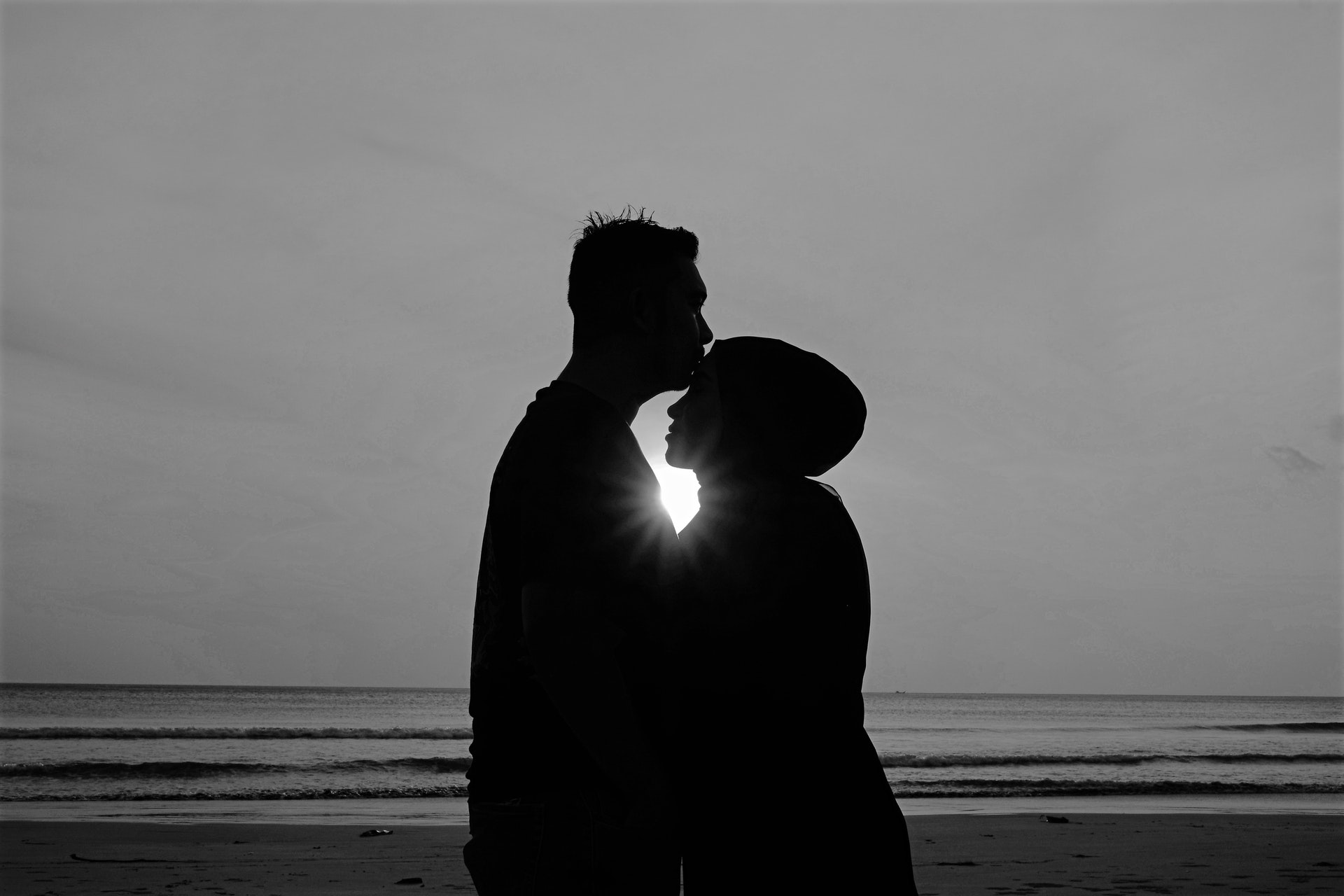 Couple embracing with the sea behind them - How to be romantic