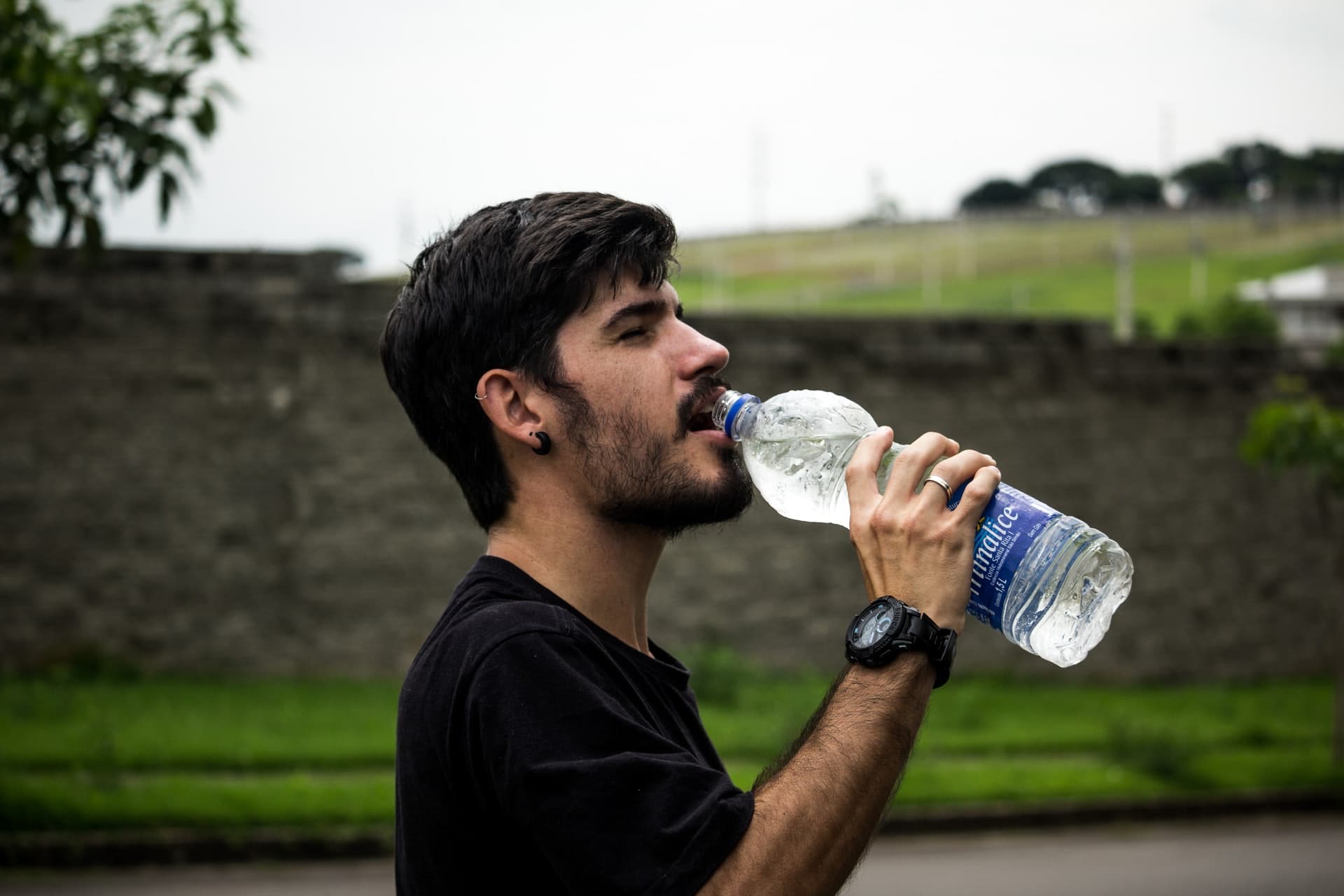 man drinking water from bottle - How to drink more water