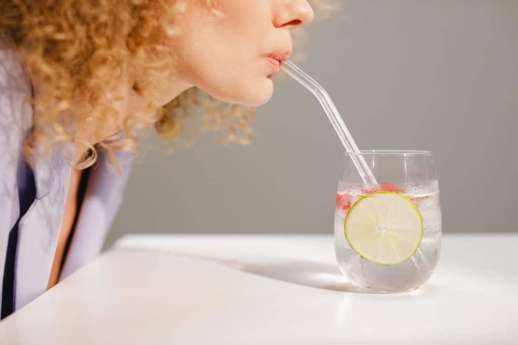 Person drinking water though a straw - Ways to drink more water - how to drink more water