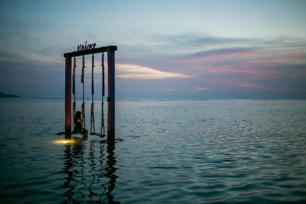 Woman on a swing over the sea looking peaceful - Inner Peace - How to find inner peace