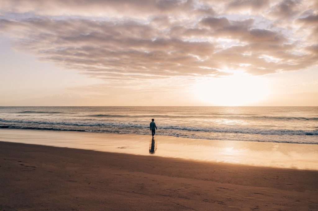 Picture of a person walking down the beach - The Ultimate Anxiety Reduction Guide