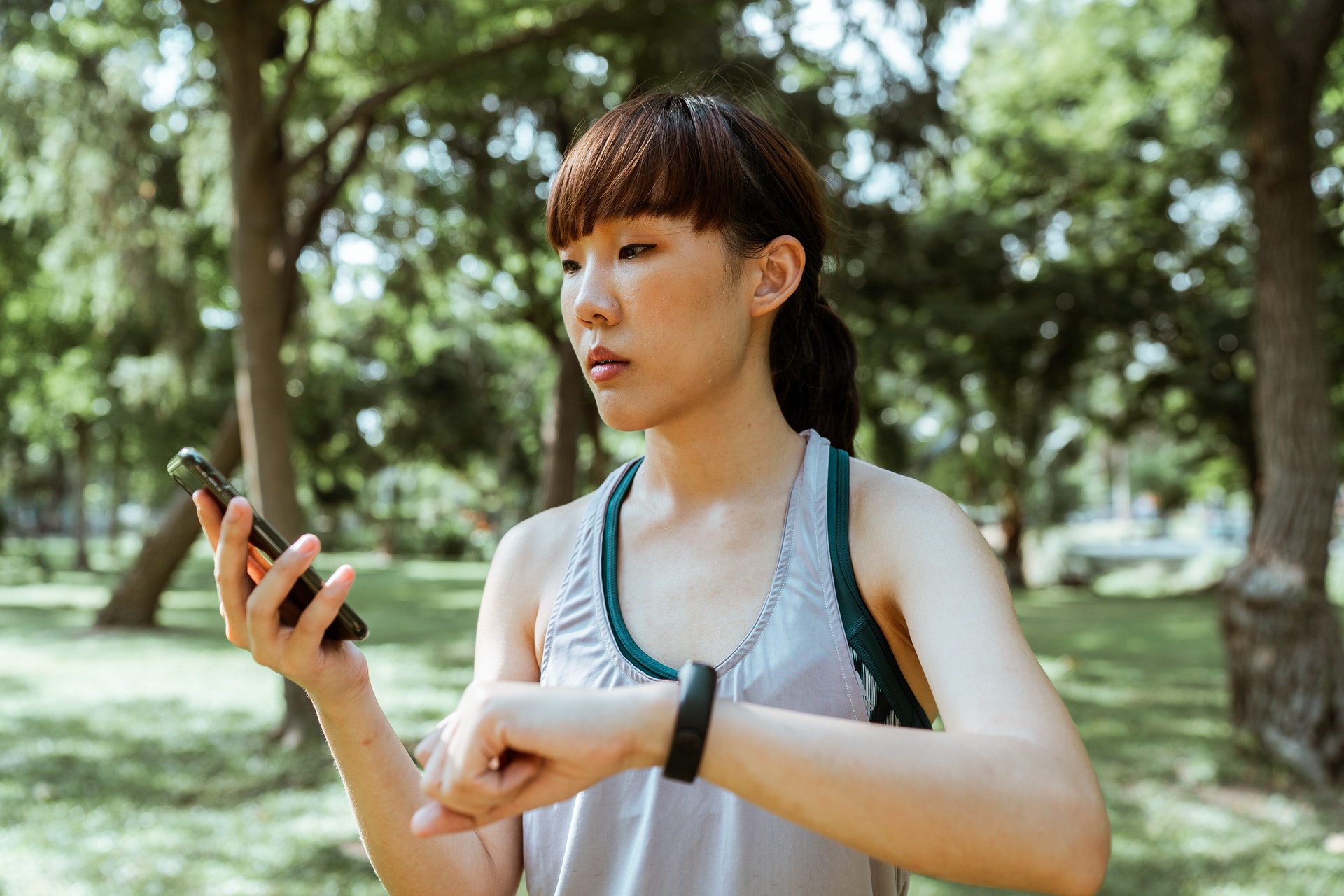 Woman looking at her phone and exercising and looking after her physical wellbeing - Physical Wellbeing Apps
