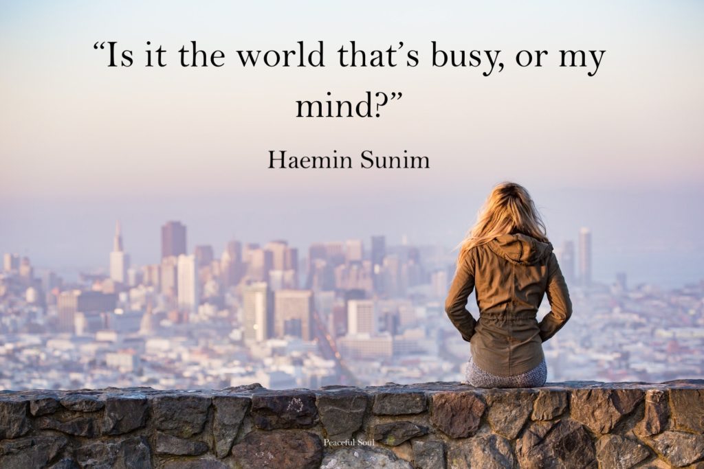 Woman sat looking a city - Quote: “Is it the world that’s busy, or my mind?” Haemin Sunim - Quotes about the mind - Peaceful Soul