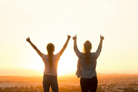 2 friends standing with raised arms and their thumbs up = article: How to Support a Friend Struggling with Their Mental Health